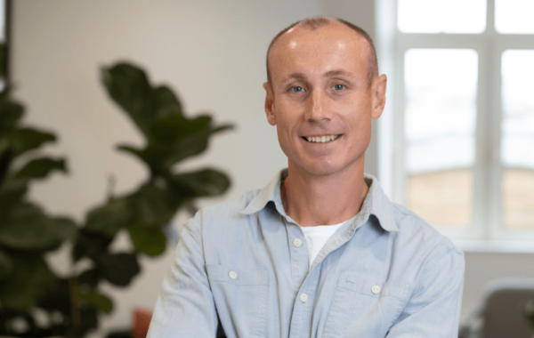 Photo of white man in blue shirt smiling in an office